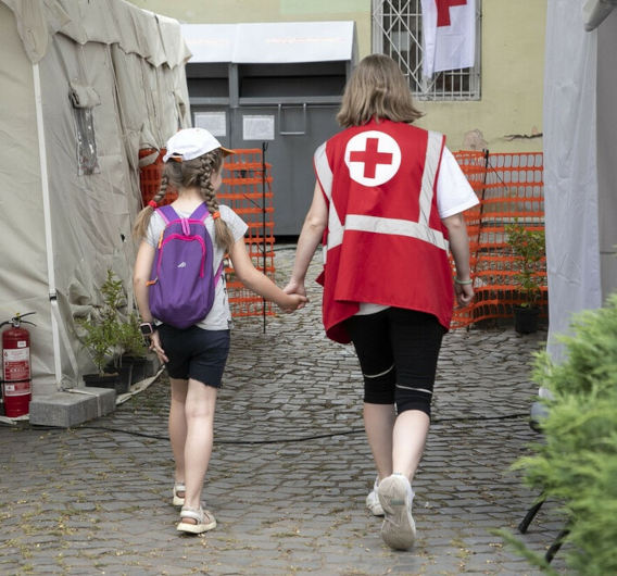 A Red Cross worker accompanies a child at the Red Cross Health Centre in Uzhhorod eastern Ukraine